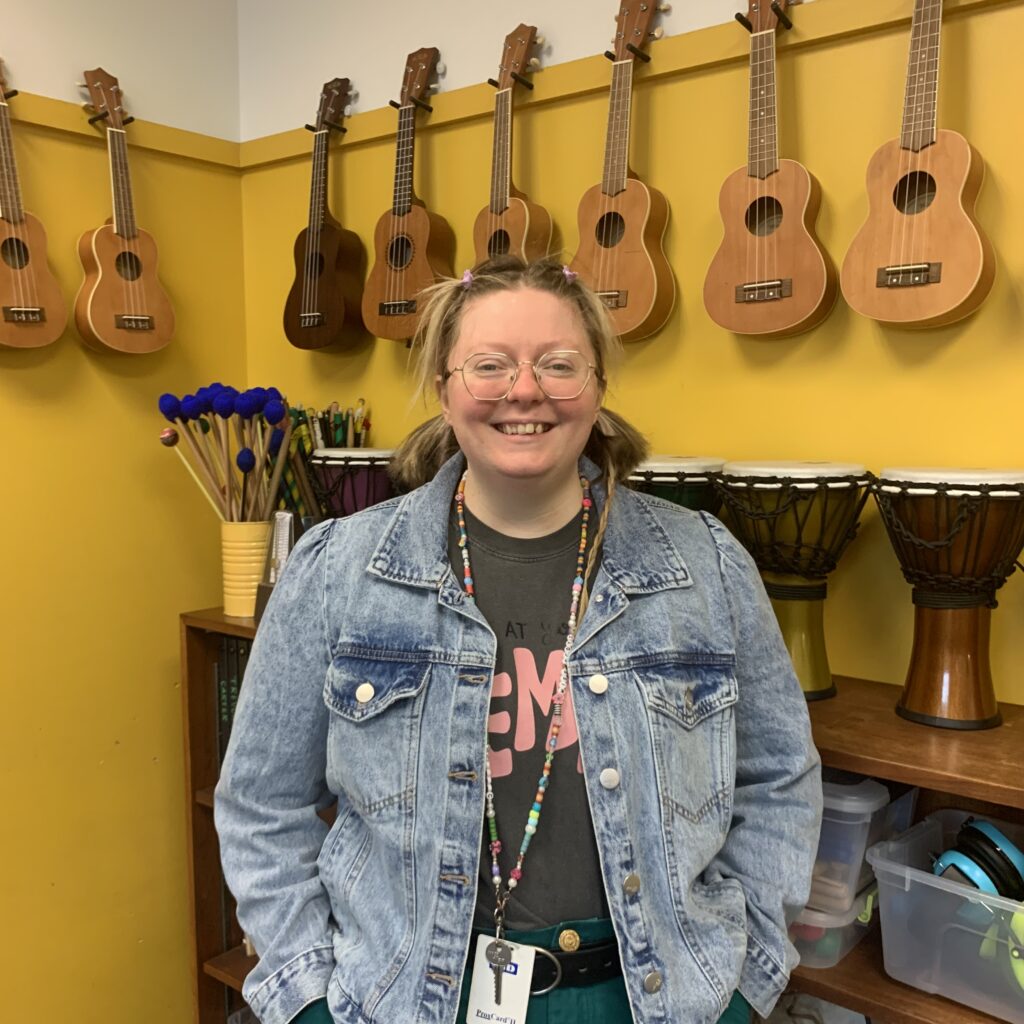 Music teacher Makayla Scott in her music room with guitars on the wall.